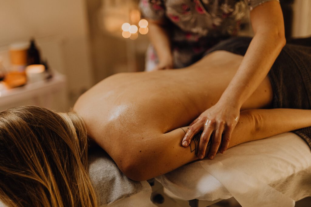 Photo d'une personne allongée sur le ventre sur une table de massage, et recevant un massage du dos